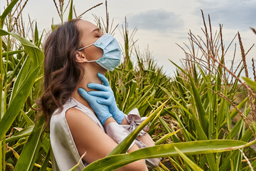 Beautiful girl with protective mask on face and medical gloves in cornfield. Coronavirus epidemic, COVID-19 quarantine concept