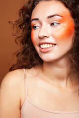 young pretty girl with curly hair posing cheerful on brown background, lifestyle people concept