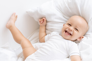 baby laughing lying on bed