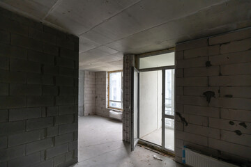 A new unfinished apartment room with the bare brick walls without decoration.