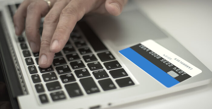 Man pays online with credit card with printed flag of Estonia. Fictional numbers
