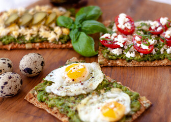 Avocado Toast with fried eggs. Colorful avocado toast over a wooden cutting table. Rustic mood. Close up. Selective focus.
