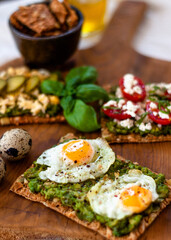 Healthy organic food. Avocado toast with greek cheese, cherry tomatoes with basil, fried eggs and cucumber. Colorful toast.   Close up. Selective focus.