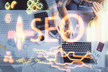 Double exposure of man and woman working together and SEO hologram drawing. Search engine concept. Computer background. Top View.
