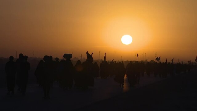 KARBALA, IRAQ - NOV 2017: Silhouette of crowd of pilgrims walking in Arbaeen pilgrimage at sunrise. Every year, millions of Shiite muslims come from all over the world to Karbala to walk Arbaeen
