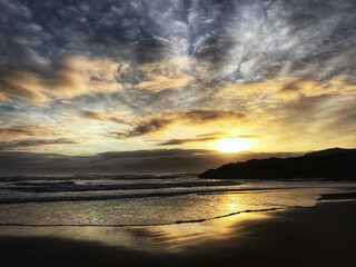 Fototapeta na wymiar Cloudy sky sunset on the beach in Bandon Oregon Pacific Ocean Coast.
