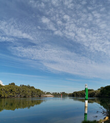 Obraz premium Beautiful view of a river with reflections of blue sky, light clouds and trees on water, Parramatta river, Rydalmere, New South Wales, Australia