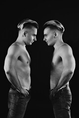 two twin brothers in blue jeans with a naked strong torso posing. black and white
