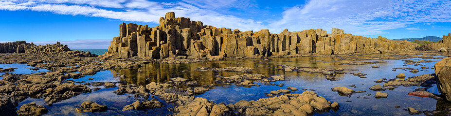 Panorama of basalt rock formations and rockpool reflections at Bombo Headland quarry, New South...