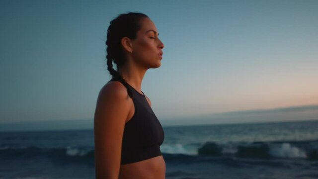 Portrait of woman deeply breathing and meditating at beach, mind setting for training, sunset at coast of Pacific Ocean