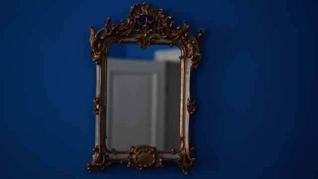 Close up of ancient mirror on blue wall. Beautiful large vintage mirror with decorative frame.