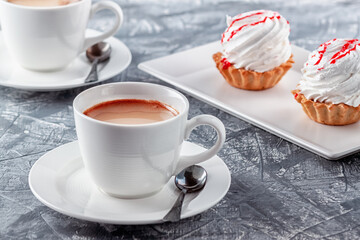 Freshly brewed aromatic coffee with cream and cake on gray background