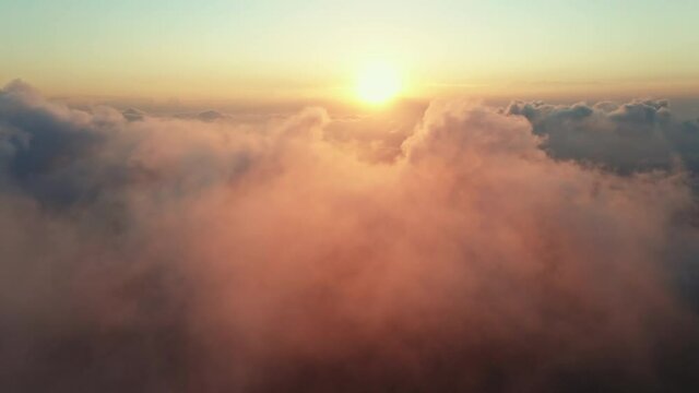 Moving white clouds blue sky scenic aerial view sunrise. Drone flies high back in blue sky through fluffy clouds in morning at bright sun summer. Sun is hidden behind clouds at fog. Relax. Nature