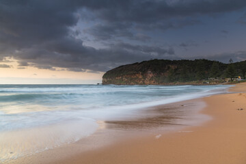 Sunrise at the beach with waves and clouds