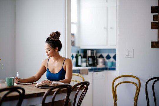 Young Asian woman working from home on kitchen dining table