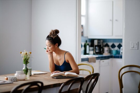 Young Asian woman working from home on kitchen dining table