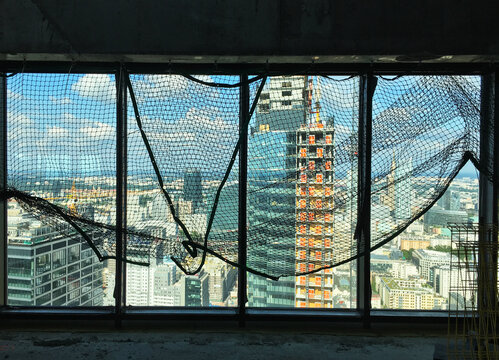 spacious view from the 42nd floor of the Skyliner Warsaw building, through the protective mesh on the window, towards the city center and the Buma building
