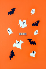 Word Boo. Wooden blocks with lettering on orange background decorated with bats and ghosts from cardboard. Vertical postcard, top view