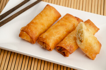 Crispy golden fried vegetable spring rolls (harumaki) on a white plate. 
