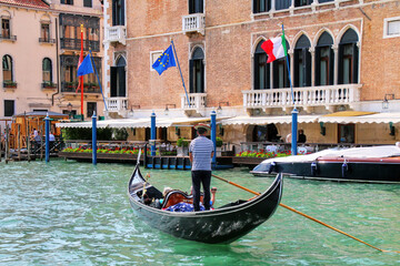 Fototapeta na wymiar Gondolier rowing gondola with tourists on Grand Canal in Venice, Italy