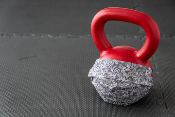 Naklejka na ściany i meble Fitness during a pandemic, fabric face mask and a red kettlebell 