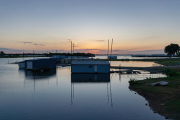 Boathouses in a marina on a calm lake at sunrise