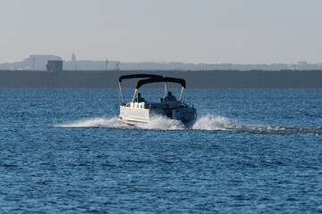 Pontoon boat with twin canopies heading out across a lake