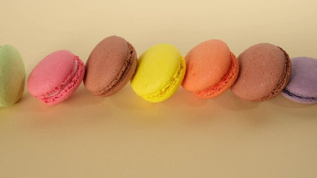 assortment of baked macarons on a beige background, dessert is in a row, camera movement to the left