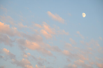 Peaceful sky at dusk, light clouds and partial moon, as a nature background
