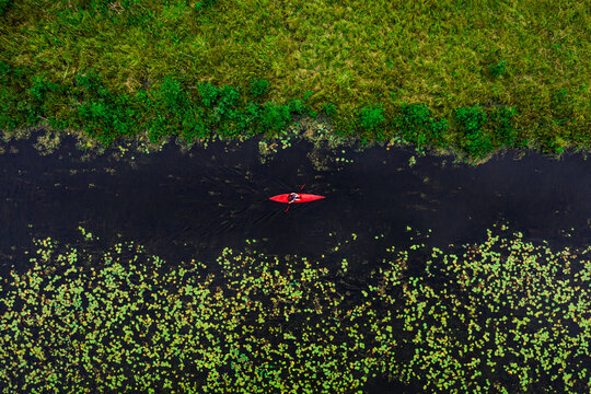 Aerial view of young man paddling in river with red kayak, shot in Lithuania.