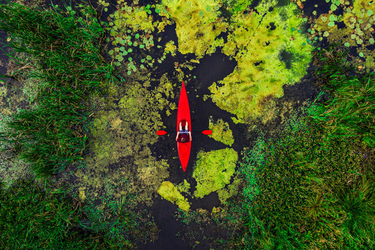 Aerial view of young man paddling in river with red kayak, shot in Lithuania.