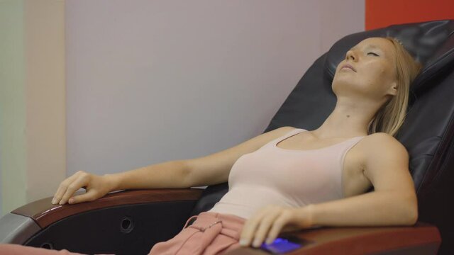 Handheld Shot Of A Young Woman Sitting In An Automatic Massage Chair