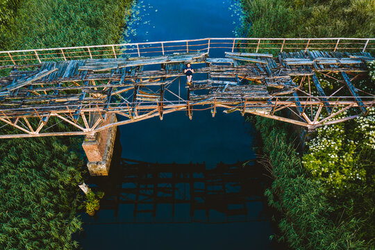 Aerial view of person lying down on old collapsed bridge in countryside.
