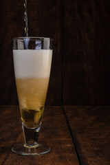 Beer served in a glass with rustic wood background.