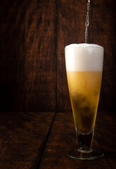 Beer served in a glass with rustic wood background.