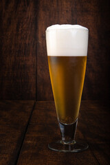 Beer served in a glass with rustic wood background.