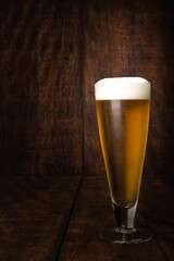Beer served in a glass with rustic wood background.