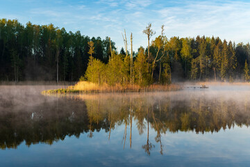 Small island in the lake during morning sunrise with fog