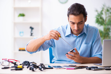 Young male technician repairing mobile phone