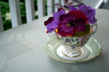 A homemade table arrangement.  Flowers are arranged in a tea cup and saucer