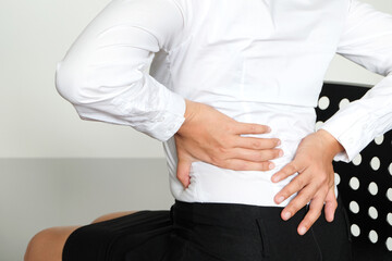 young woman sitting have back pain and sore waist concept of pain relief and health care