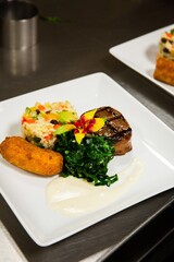 Brazilian food, colorful rice, fried banana , steak, collard greens, plated up dinner at restaurant's kitchen