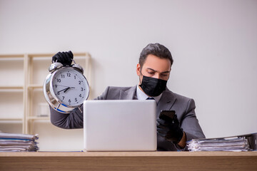 Young male employee in the office during pandemic disease
