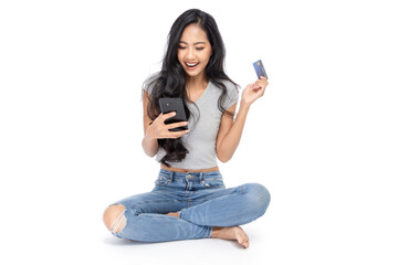 Isolated woman sit on the floor holds a credit card and a smartphone