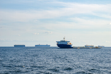 Fototapeta na wymiar Project cargo ship anchors in the open sea among the several types of commercial ships.