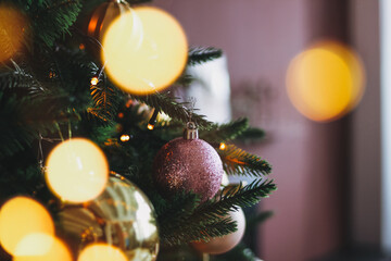 Decorated Christmas tree in gold and purple toys with lights bokeh textured background