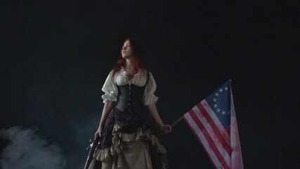 Young patriot girl in historical dress with pistol and flag