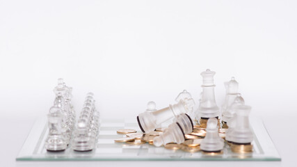 Tablero de ajedrez con piezas transparentes en formación de juego con monedas doradas © Carlos Hurtado