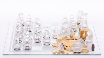 Tablero de ajedrez con piezas transparentes en formación de juego con monedas doradas © Carlos Hurtado