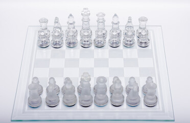 Tablero de ajedrez en formación de partida con piezas transparentes en fondo blanco © Carlos Hurtado